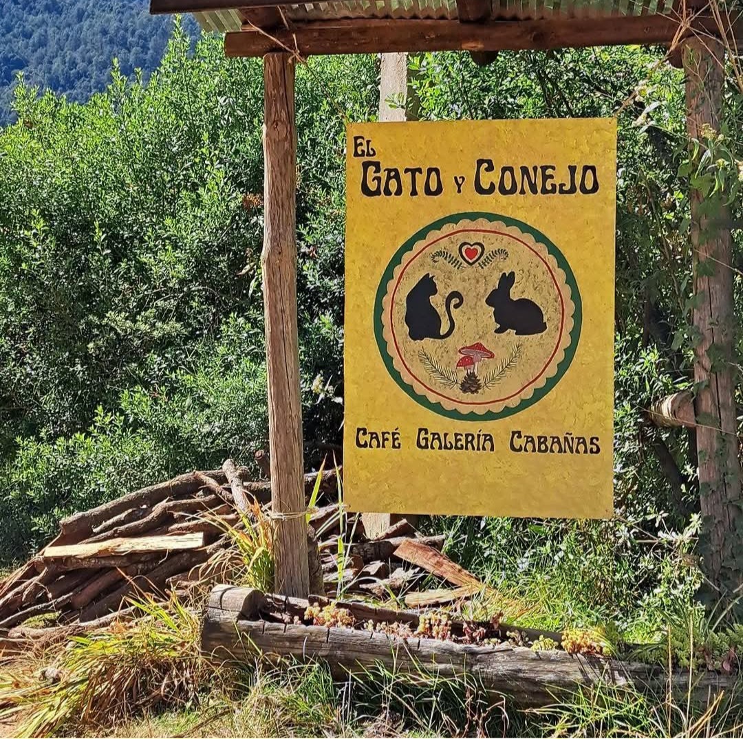 Yellow sign that says El Gato y Conejo Cafe Galeria Cabanas with a natural background