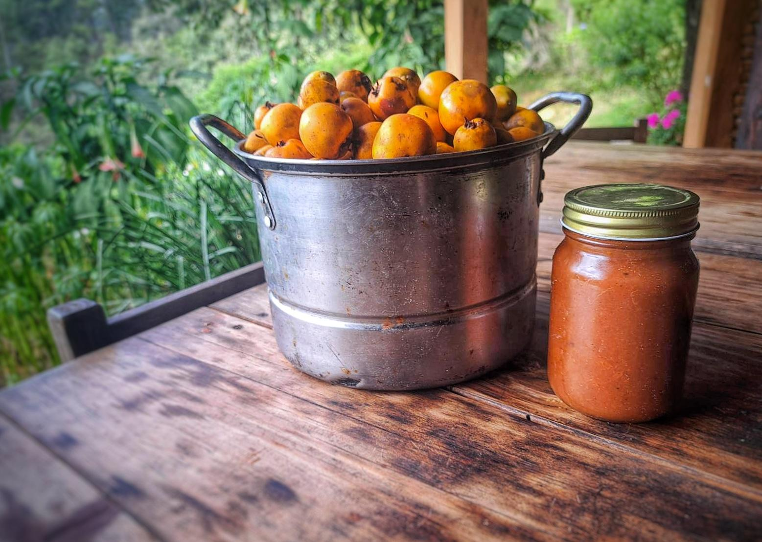 Pot full of tejocotes with a jar of apple butter